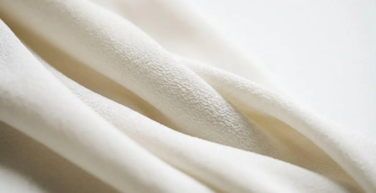 Extreme close-up of high-performance synthetic wedding dress fabric showing wrinkle-resistant texture and drape